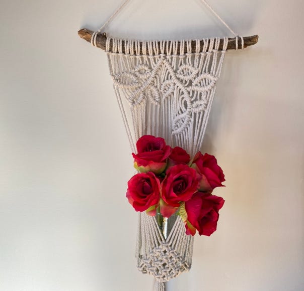 Hanging macrame plant pot holder in off-white hung from an organic piece of drift wood