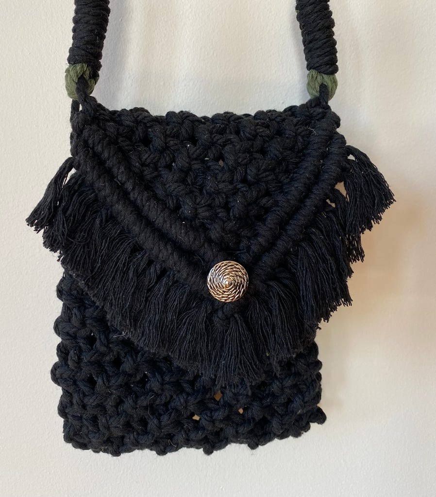 A shiek macrame black cocktail pouch with decorative flap-over on a long macrame strap