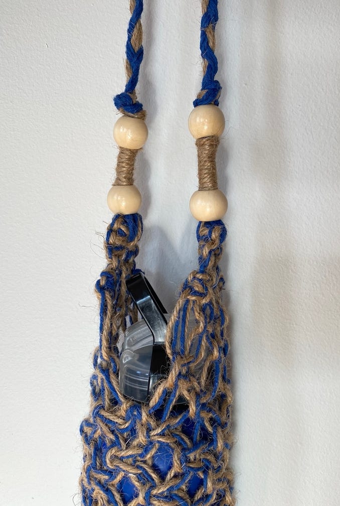 Beautifully crafted blue macrame drink bottle holder interlatce with twine with an adjustable strap