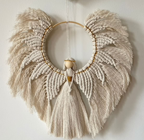 A mesmerising macrame angel with ornate off whte full body wings, inerlaced with golden thread